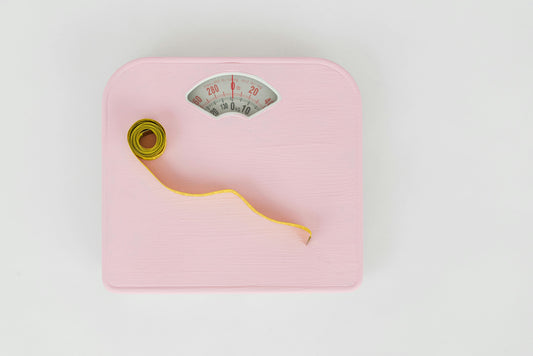 A scale with measuring tape on top of it accompanying an article about whether constipation can cause weight gain