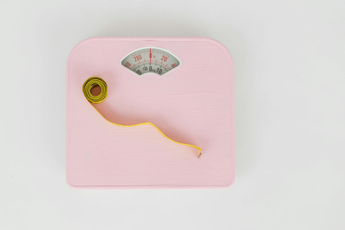 A scale with measuring tape on top of it accompanying an article about whether constipation can cause weight gain